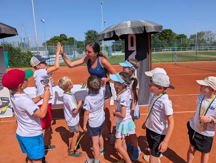 Kindergruppe mit Trainern auf dem Sandplatz