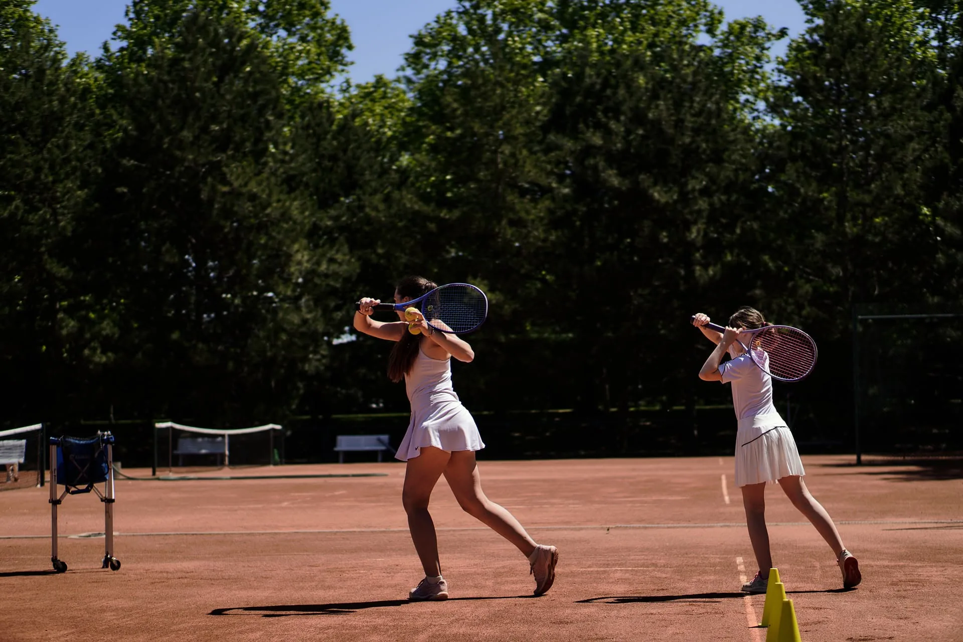 Zwei junge Spielerinnen beim Rückhandtraining auf dem Sandplatz